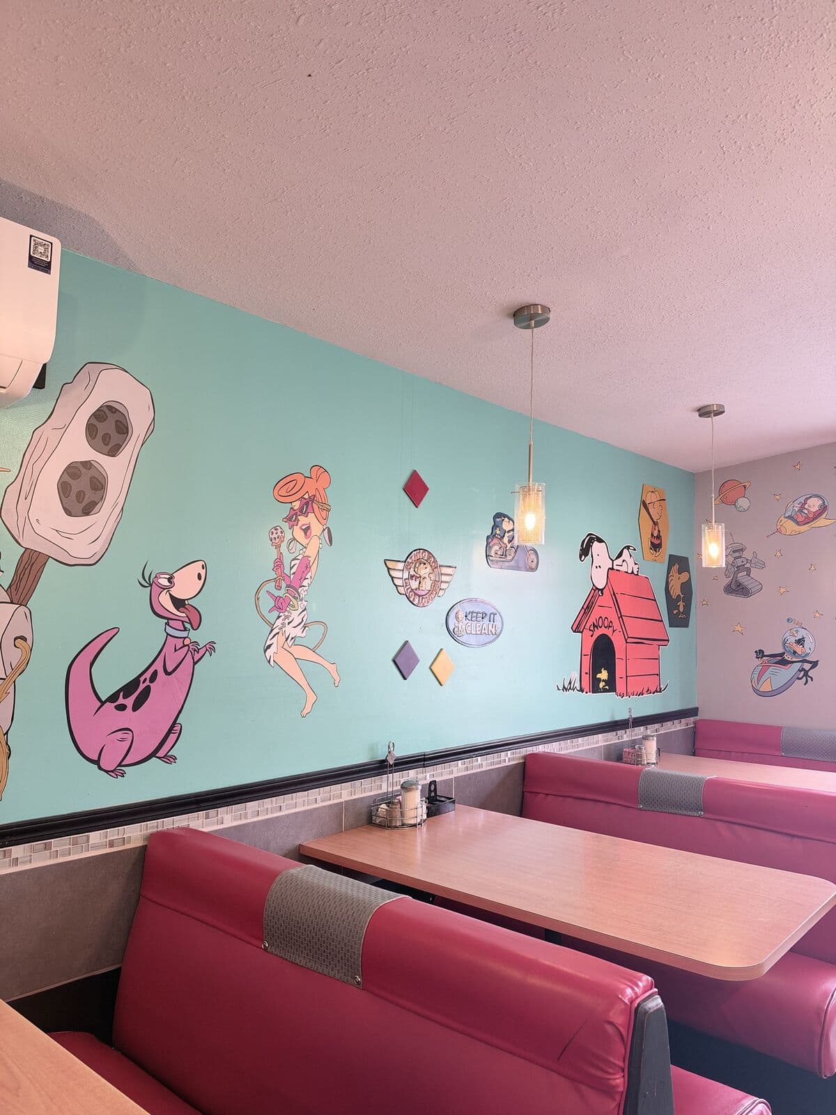 Red booths under the teal cartoon walls